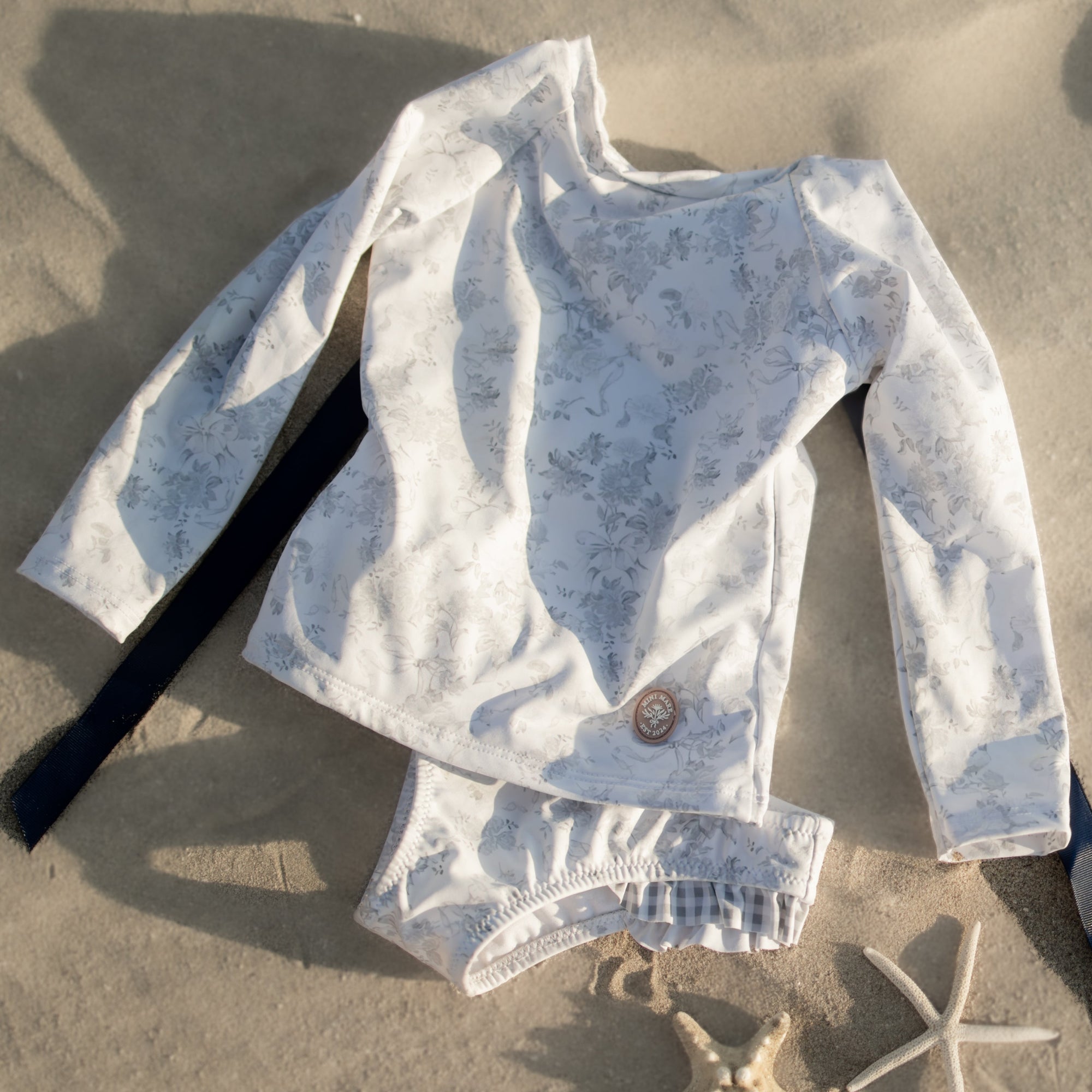 Light blue baby swimsuit on sand with starfish