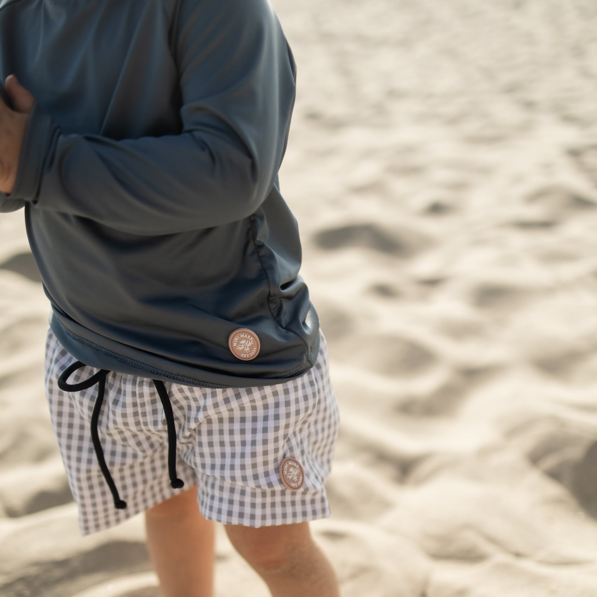Person wearing checkered shorts on a sandy beach